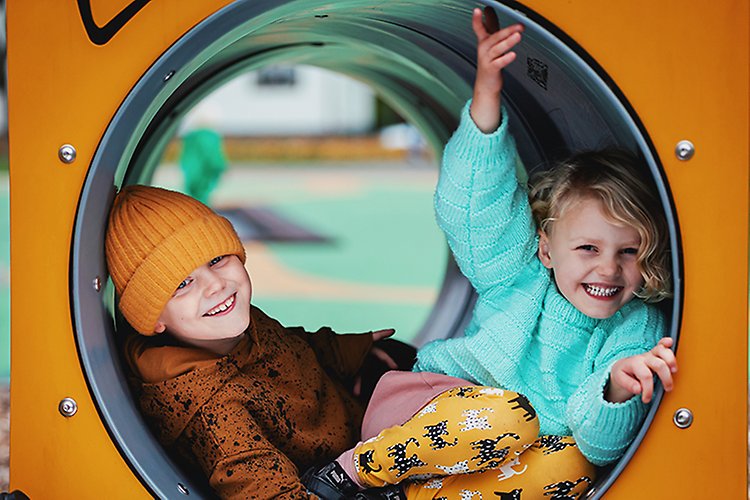 Bild på två barn som leker i en lekpark. 
